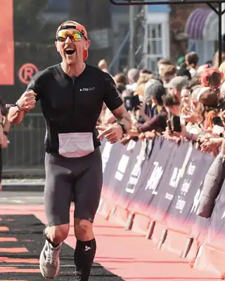 Dr Tom crossing an Ironman finish line